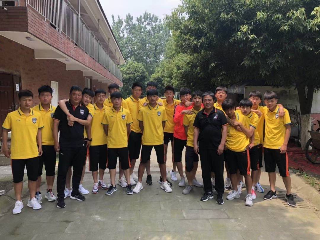 一群穿黄色球衣的少年在教学楼前合影